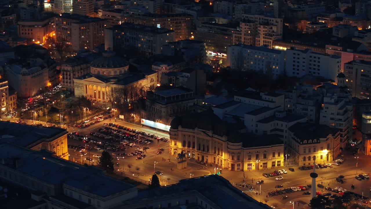 Aerial drone view of Carol I University Foundation in the night. Main building with Carol I statue in front of it, roads and buildings. Illuminated Bucharest city, Romania
