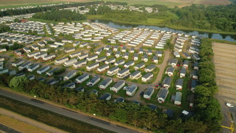establishing rising drone shot of static caravan holiday home park with small lake and trees in north norfolk uk east coast