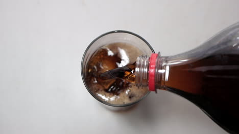 refresco de cola vertido en un vaso transparente con hielo