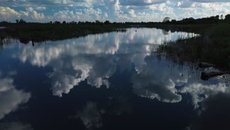 static wide establishing shot of cumulous clouds mirrored on a pond surface