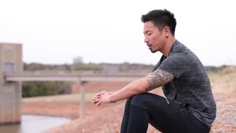 asian-male-sits-on-hill-looking-out-to-the-water