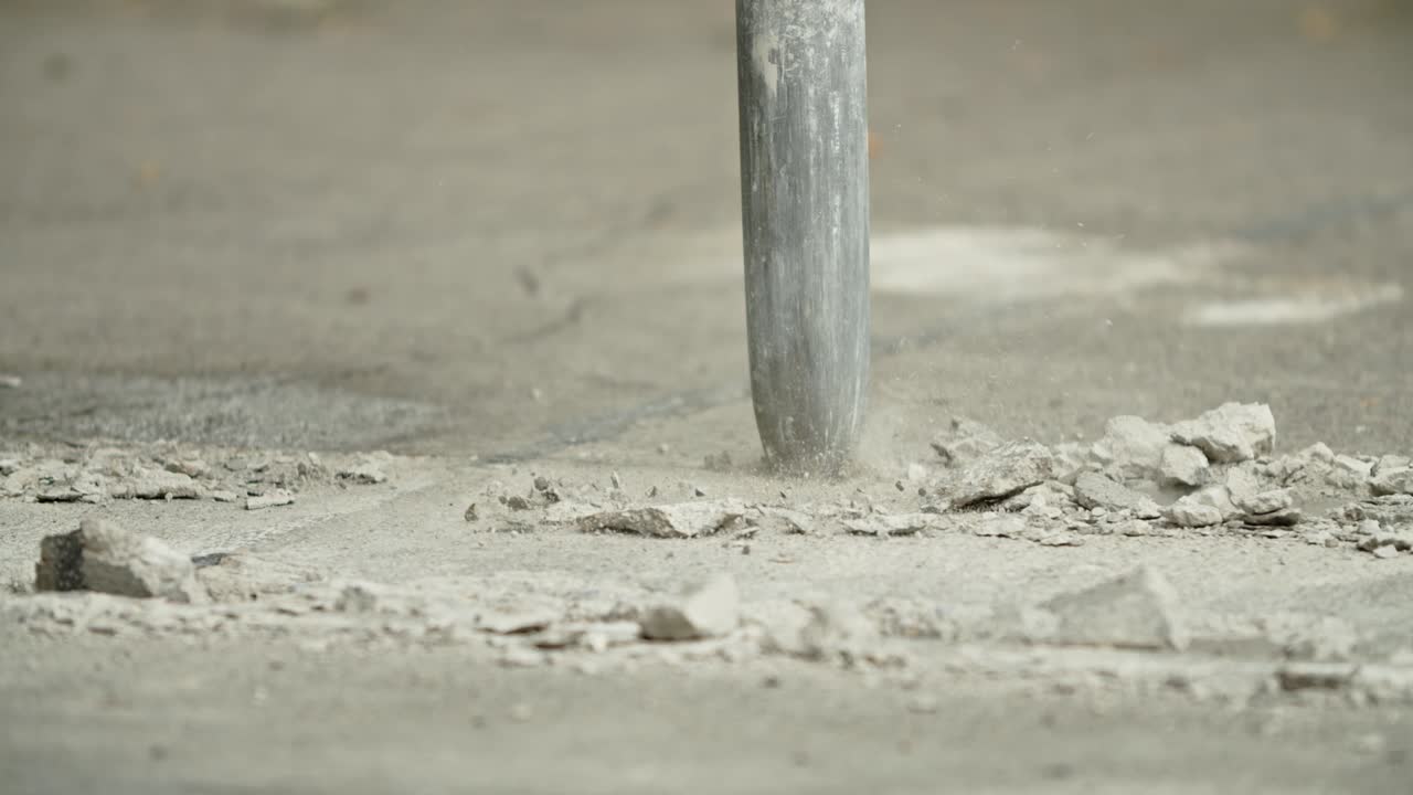 Close-up of excavator hydraulic arm rock breaker working on concrete road