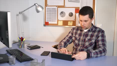 hombre trabajando en su escritorio con una tableta
