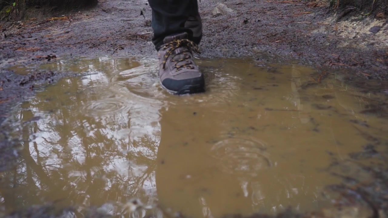 Man loopt door modderpoel met wandelschoenen