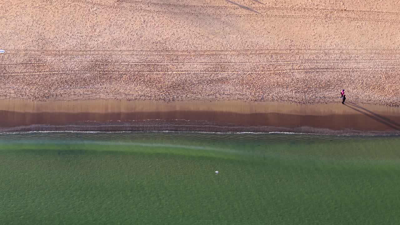 The baltic sea coast in sopot, poland, with winter waves and beachgoers , aerial view