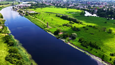 canal flowing through farmland with trees lining water and midday sky reflections
