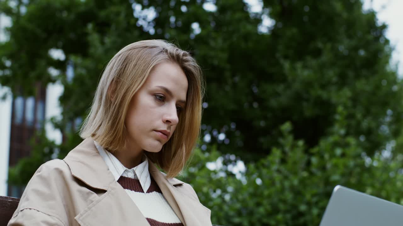 молодая женщина работает на ноутбуке в парке