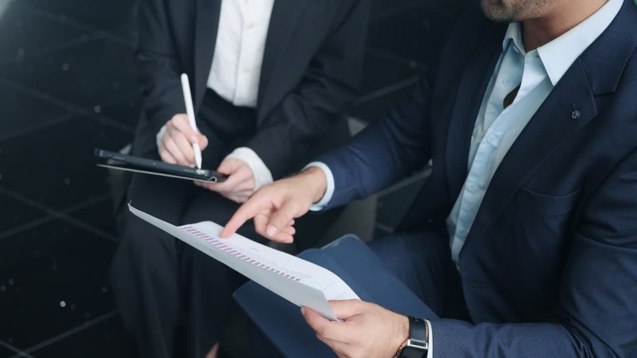 Businesspeople In Suits Reviewing A Printed Document With Charts And A Digital Tablet With A Stylus. - closeup shot