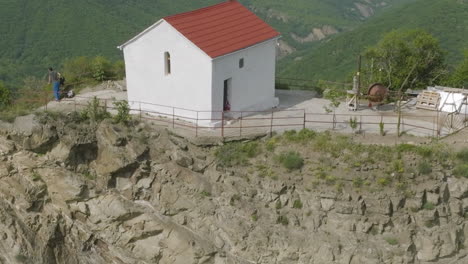 an eremite standing by the house-resembling church hidden in wilderness