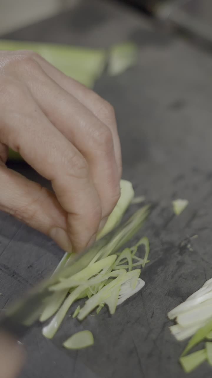 Close-up of slicing green vegetables with a knife on a cutting board