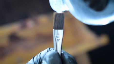 limpieza de primer plano del pincel de pintura al óleo de un artista con aguarrás y guantes