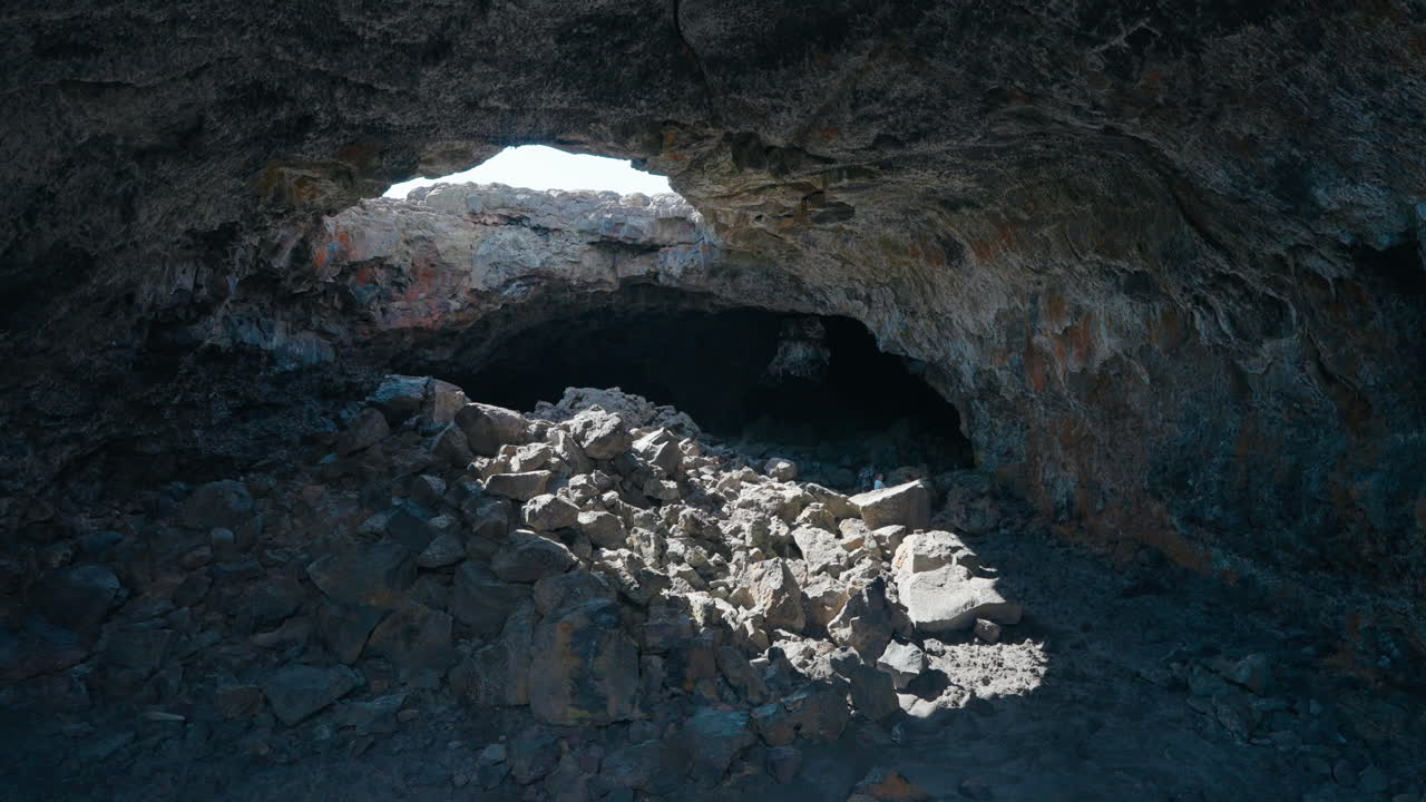 Exploring a vast rocky cave with a large skylight
