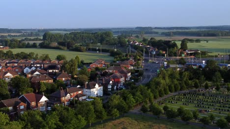 aerial view across wealthy british neighbourhood surrounded by public park lit by morning sunrise