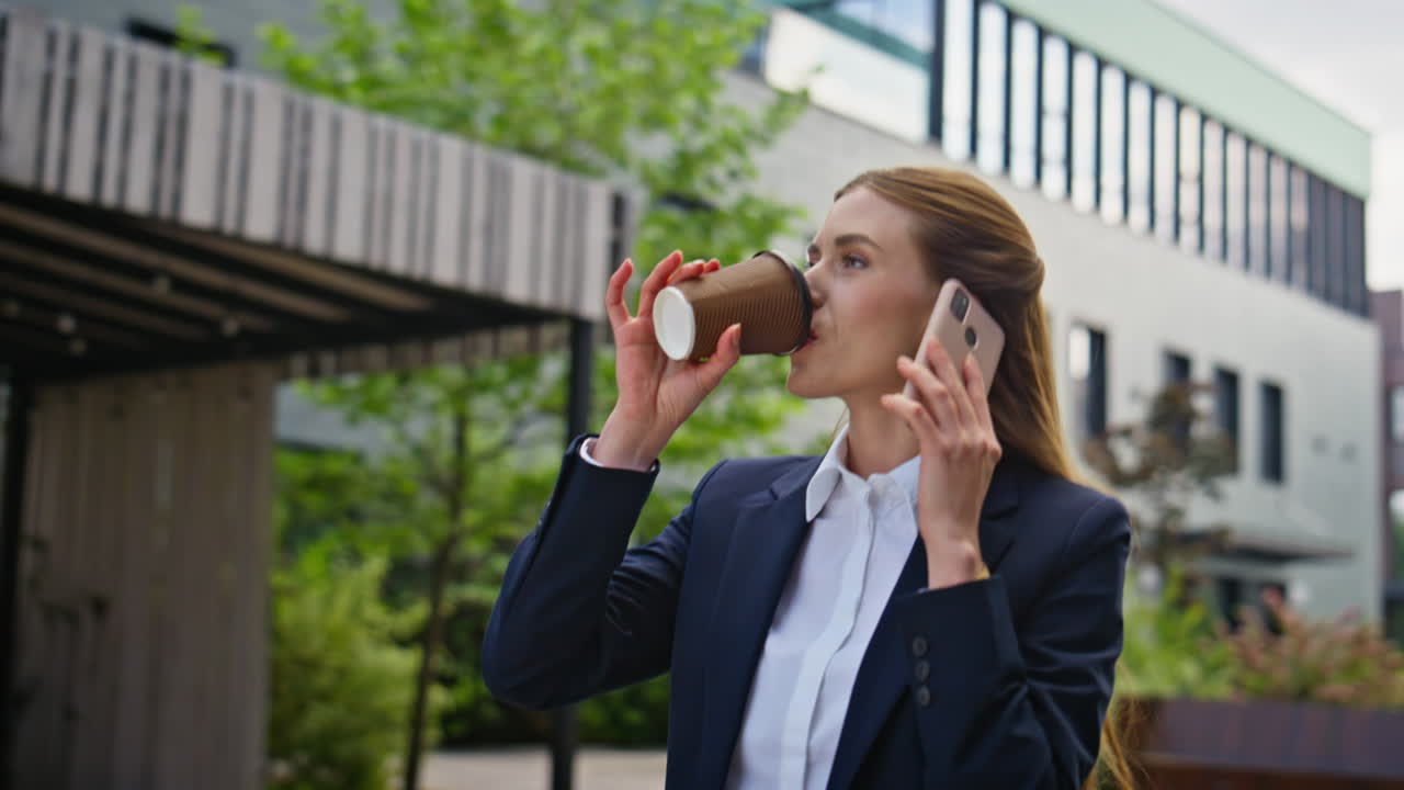 Joyful entrepreneur chatting mobile phone drinking coffee on go closeup