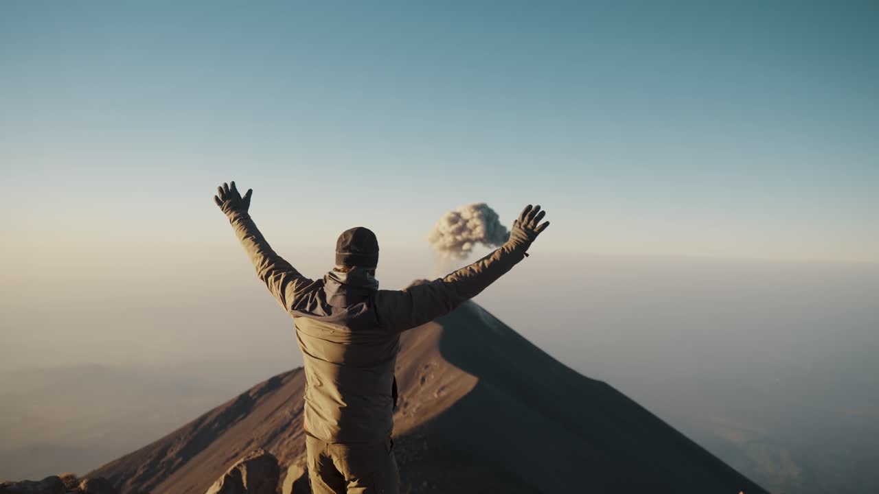 excursionista en el volcán acatenango levantando los brazos al amanecer, mirando el volcán fuego en antigua, guatemala