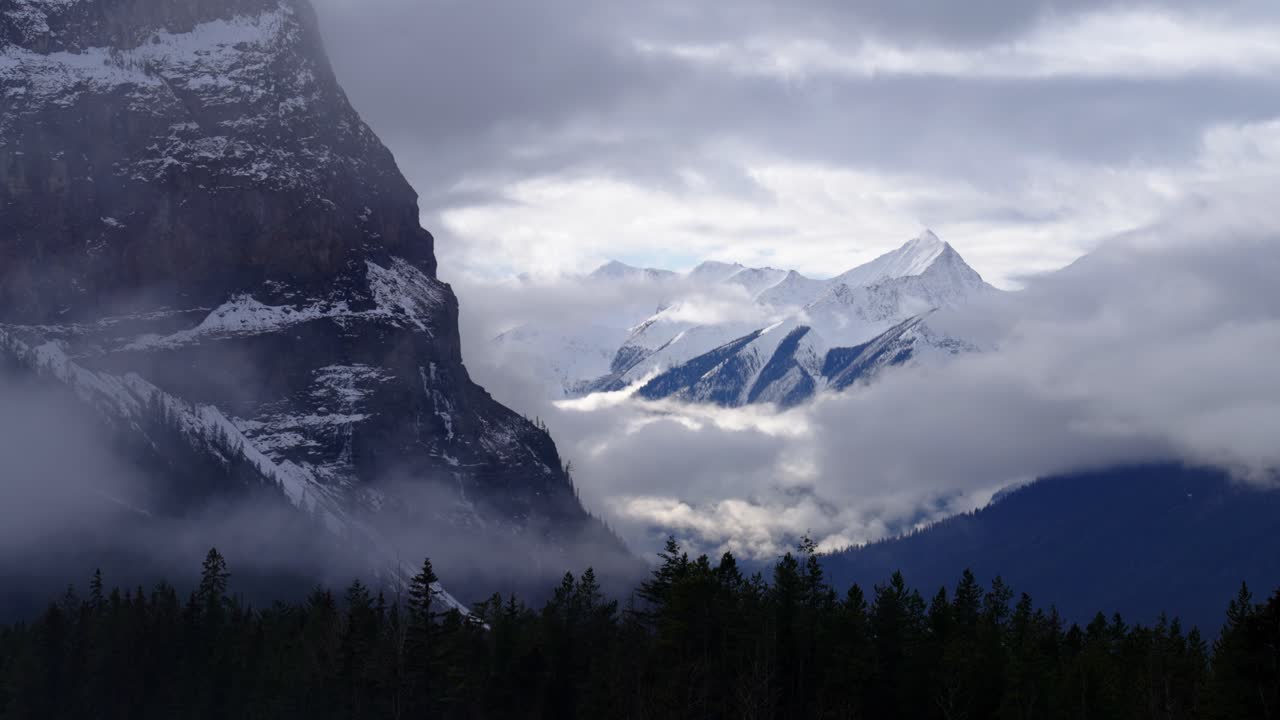 Una scogliera, nuvole basse e una cima innevata nel Parco nazionale di Yoho, Canada, in inverno