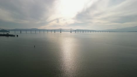 ascending aerial drone shot that captures the richmond–san rafael bridge stretching across the bay near point molate.