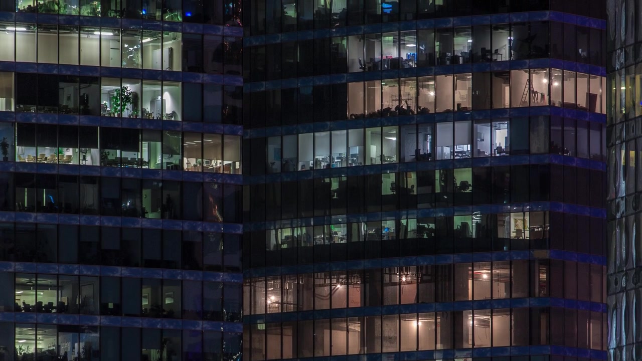 Vista aproximada de janelas de escritórios iluminadas em arranha-céus do Centro Internacional de Negócios da Cidade, timelapse noturno visto de cima.