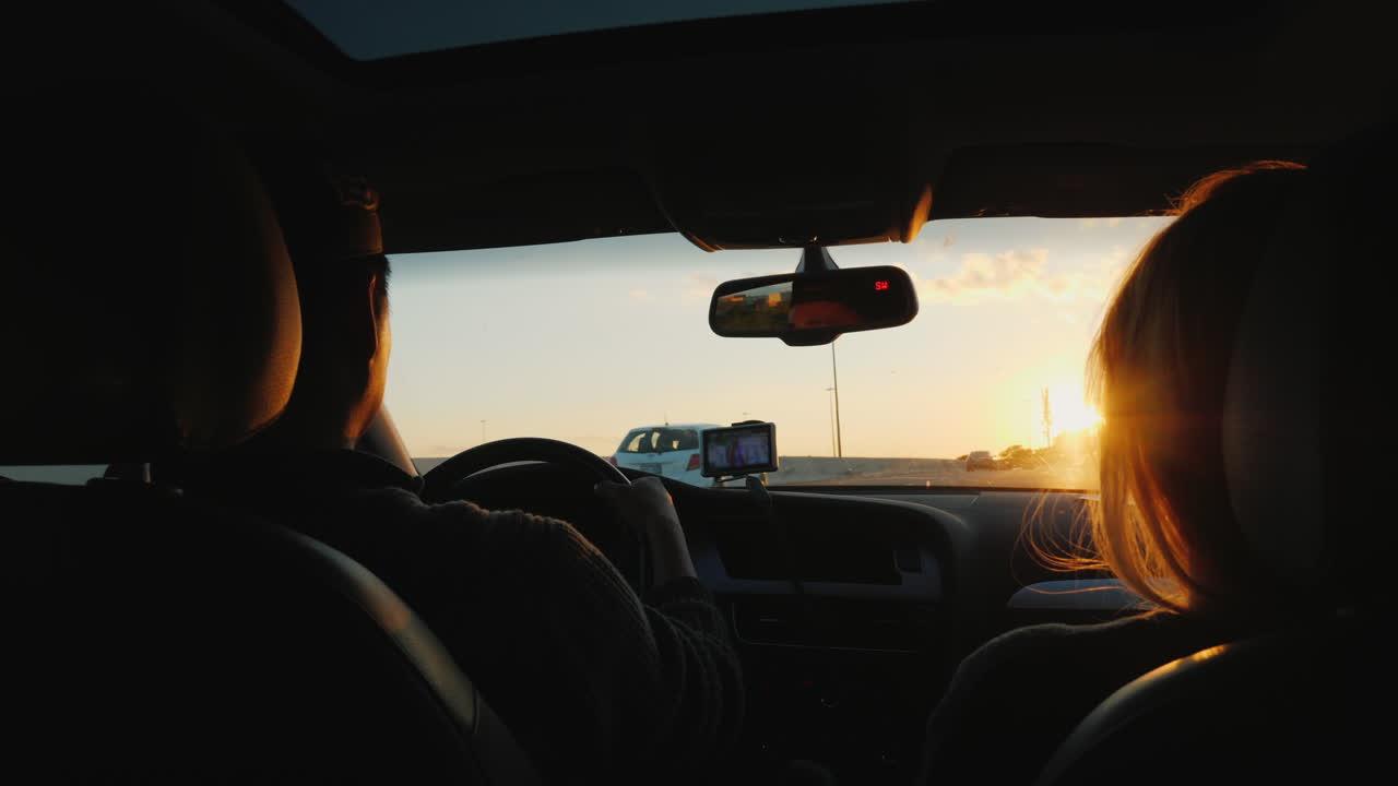 pareja conduce por la carretera al atardecer