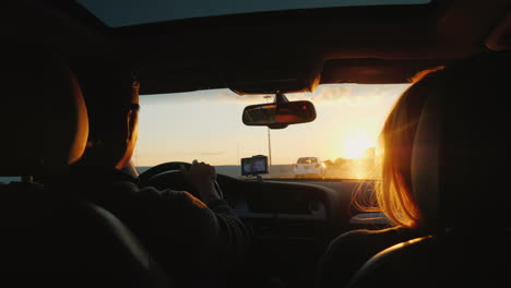 pareja conduce por la carretera al atardecer