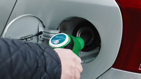 hand of a gas station man is putting gasoline into a car