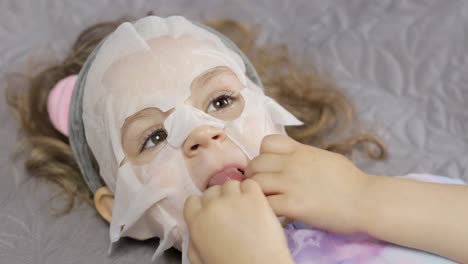 teen girl applying moisturizing face mask. child kid take care of skin with cosmetic facial mask