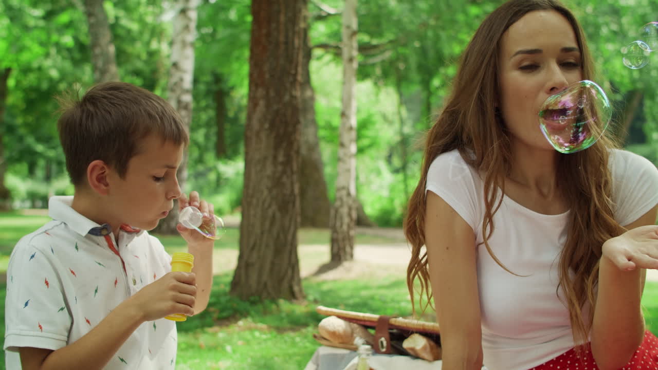 madre con los niños sentados en una manta en el parque. familia divirtiéndose al aire libre