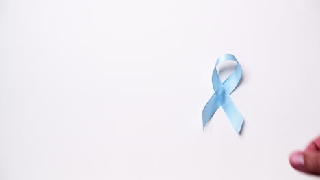 detail of male hand placing ribbon in light blue color on white background