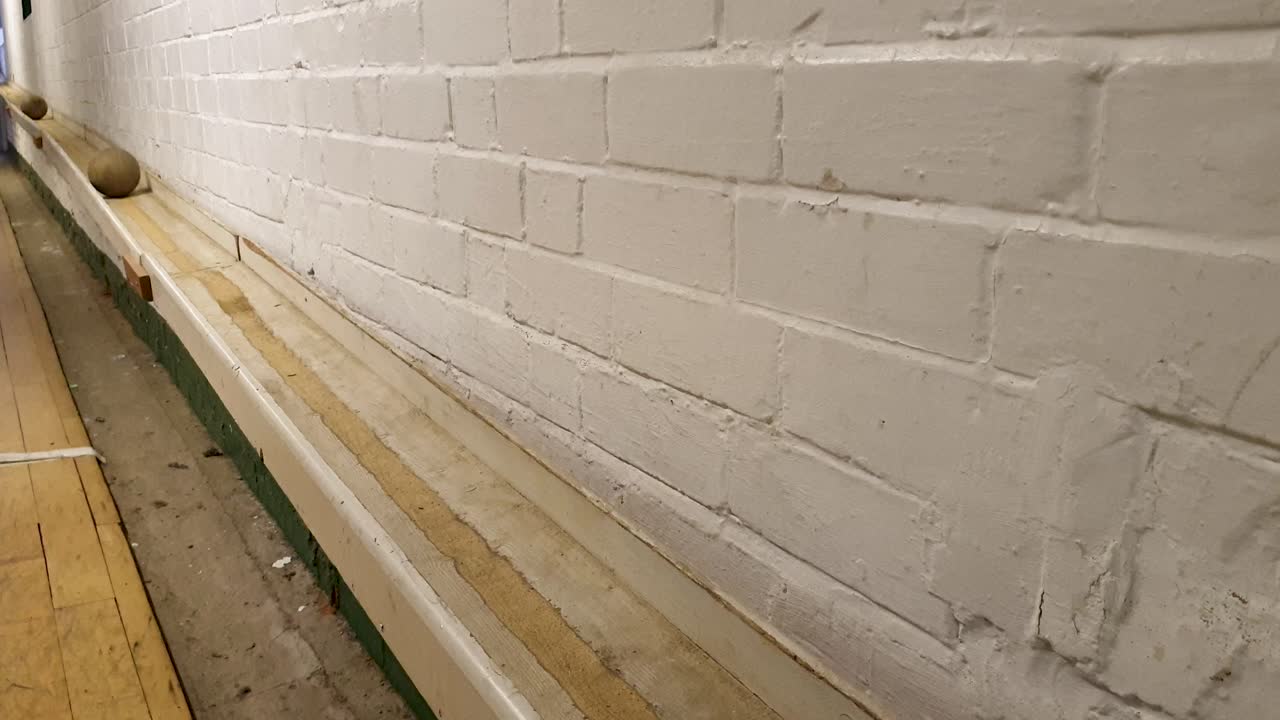 전통적인 영국 술집 골목에서 굴러내리는 나무 스키틀 공의 근접 시각