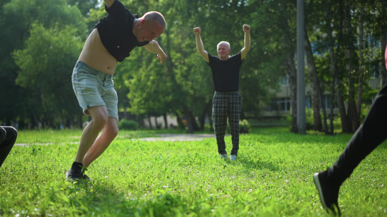 una familia disfruta de un juego de fútbol al aire libre mientras el hijo pequeño patea la pelota, el padre celebra enérgicamente y el abuelo salta con alegría con las manos en alto