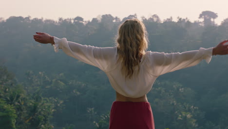 mujer feliz celebrando con los brazos levantados mirando a la selva tropical al amanecer sintiendo alegría en las vacaciones de verano aventura disfrutando de un nuevo día en el paraíso