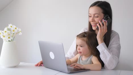 a beautiful asian mother busy working at home while looking after and teaching her children on a lap a beautiful asian mother busy working at home while looking after and teaching her children on a laptop computer