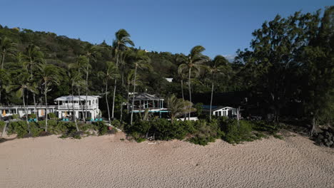 Aerial-Dolly-pan-to-the-right-of-bungalows-along-the-beach-in-a-tropical-paradise