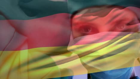 Animation-of-waving-germany-flag-against-caucasian-female-surgeon-wearing-surgical-mask-at-hospital