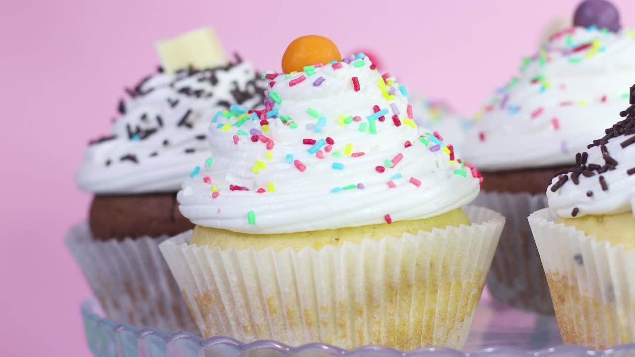 크림과 다채로운 어리로 맛있는 컵 케이크를 먹습니다.