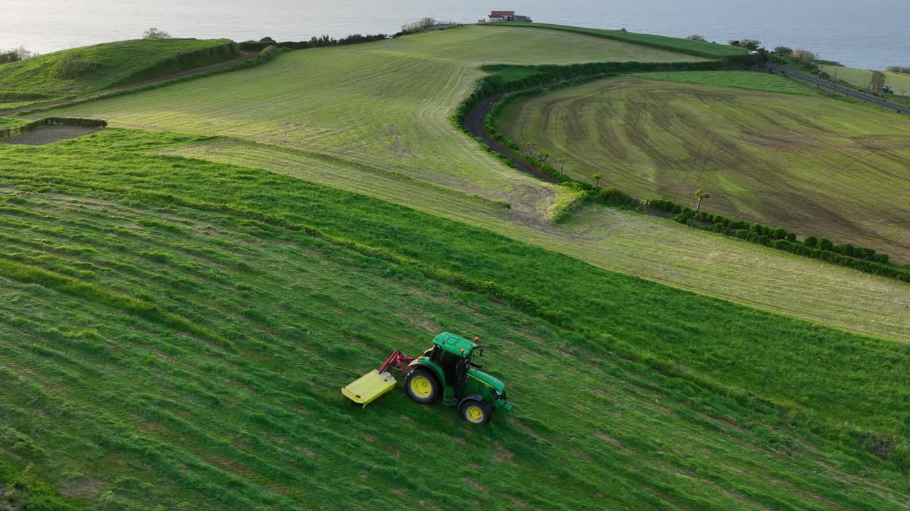 Observing a Tractor Operating Within Sao Miguel Island's Agricultural Terrain in Portugal - Aerial Tracking Shot