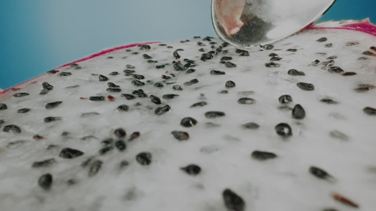 Eating Dragon fruit slice with a spoon on blue background