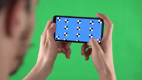 caucasian man zooms by fingers content in smartphone with tracking markers on display on chroma key