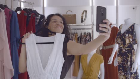 Mujer-Latina-Feliz-Aplicándose-Un-Vestido-Blanco-A-Sí-Misma-Y-Haciendo-Una-Foto-Selfie