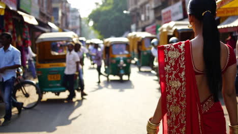 woman in red sari walks through a busy indian city street