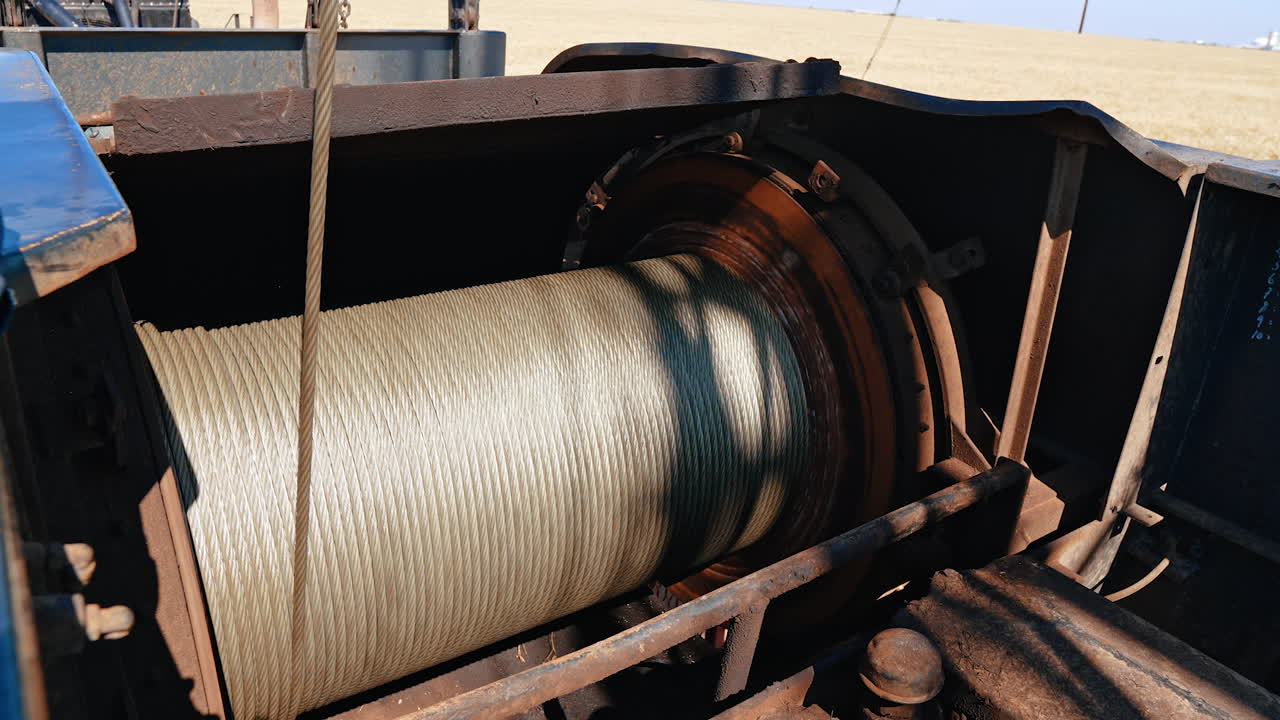 Huge roll with the metal wire unwinding. Close up view on the equipment used in oil or gas drilling.