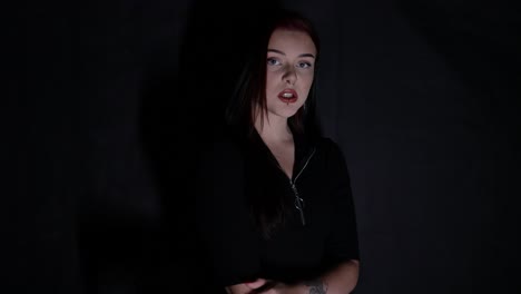 attractive young caucasian woman singing in front of black background while being lit in white light