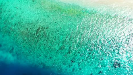 blue turquoise sea texture with calm clear water over coral reefs, reflecting sunlight of a hot summer day in caribbean