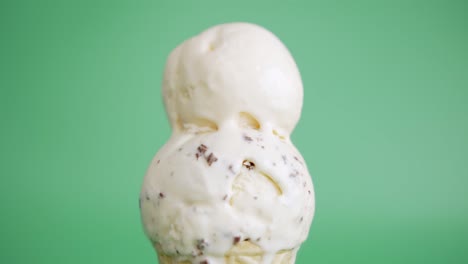 hands scoop ice cream vanilla on top chocolate chip in waffle cone.