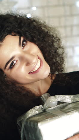 gift box new year day celebration. young attractive woman with gift box near fireplace vertical video