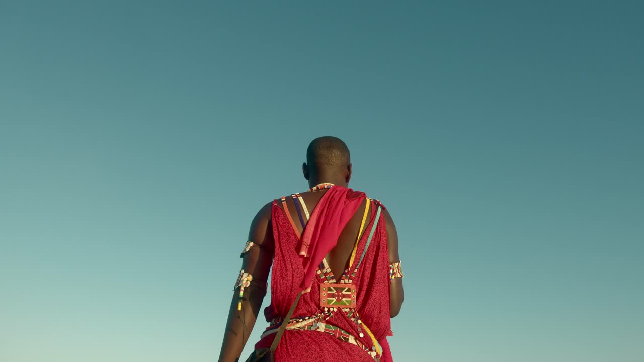 vista trasera de un guerrero maasai indígena con ropa tradicional roja y joyas tribales en watamu, kenia