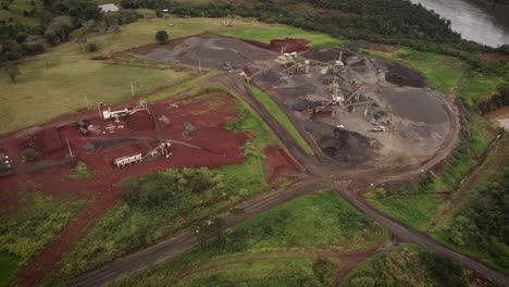 high-level drone footage of an open-pit quarry in brazil next to the iguazu river where a truckload of rocks leaves