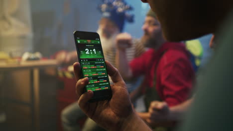 group of men reacting to sports betting results on a smartphone