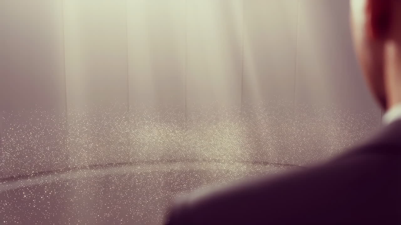 Person in a suit looking at glowing particles in a light-filled room