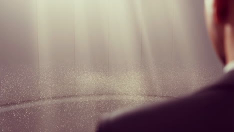 person in a suit looking at glowing particles in a light-filled room